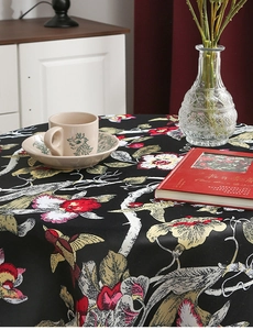 Nahaufnahme der Vintage-Blumen und Vogelmuster auf hitzebeständiger schwarzer Stofftischdecke