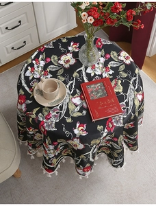 Nahaufnahme einer Vintage-Blumen-Tischdecke mit weißen Quasten auf einem runden Holztisch