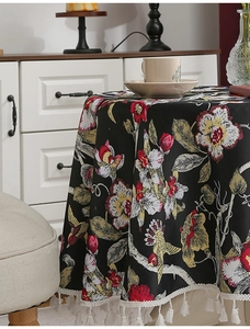 Detail der Tischdecke mit Blumen- und Vogelmuster und weißen Quasten am runden Tisch