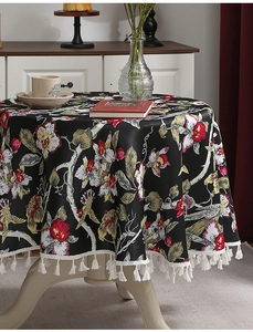 Detail einer floralen runden Tischdecke mit weißen Quasten auf dunklem Vintage-Stoff