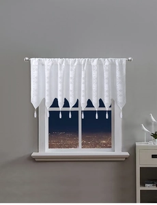 Detail of white lace valance curtain featuring geometric patterns and fringe tassels