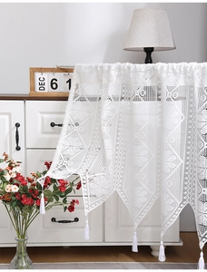 Close-up of white lace valance featuring hollow floral patterns and elegant tassel trim