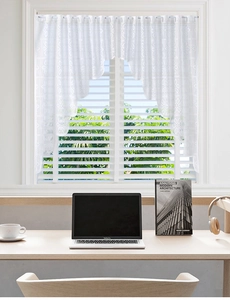 Close-up of white lace window valance with geometric floral patterns and fringe edge