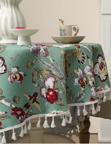 Detail der salbeigrünen Tischdecke mit Kolibri-Blumenmuster und weißen Fransenquasten