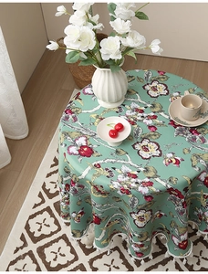 Detail der petrolfarbenen runden Tischdecke mit Blumenmuster und weißer Spitzenquaste