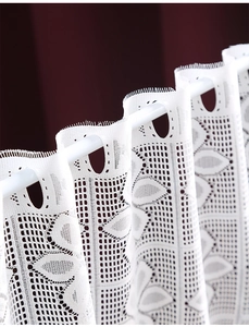 Close-up of white lace curtain showing intricate floral crochet and mesh details
