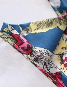 Makroaufnahme der feinen Saumnaht auf einer blauen Tischdecke mit abstraktem Blumenmuster