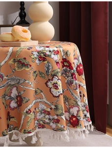 Detailaufnahme der orangefarbenen Tischdecke mit Blumenmuster und weißen Fransenbordüren