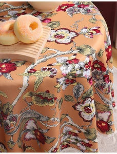 Detail einer runden geblümten Tischdecke mit orangefarbenem Vogelprint und Quasten