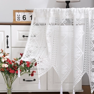 White lace window valance with hollow floral patterns and tassels in home setting