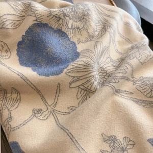 Detailed close-up of beige pashmina scarf featuring elegant blue floral print patterns