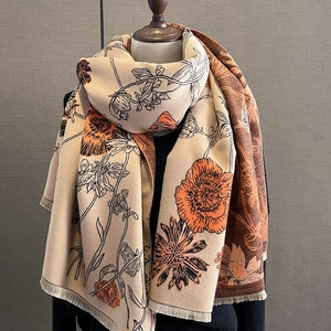 Close-up of double-sided cashmere-like scarf with orange floral patterns and fringed edges