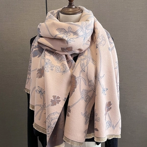 Macro detail of the soft pink cashmere-like scarf with blue floral prints and fringes