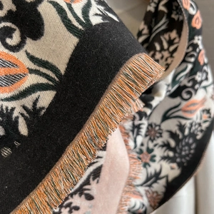 Close-up of thick winter scarf showing detailed floral jacquard weave and colorful fringes