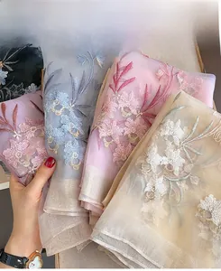Detail of floral embroidery on lightweight silk wool scarves in various pastel colors