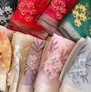 Detailed macro view showing diverse floral embroidery on translucent silk wool fabric
