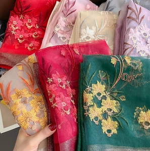 Detail of silk wool scarves with floral embroidery and metallic edges in various colors