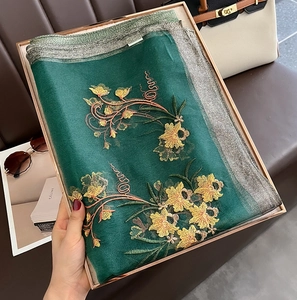 Detailed embroidery on emerald green silk wool scarf inside a luxury gift box