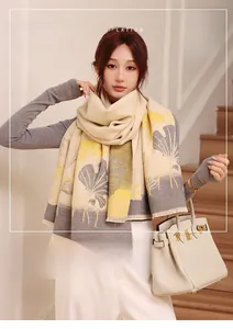 Detail of warm beige scarf with yellow ginkgo leaf pattern and delicate tassel edge