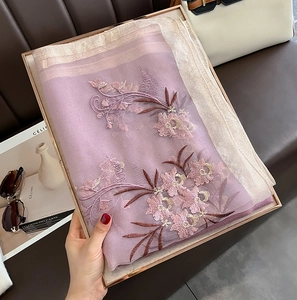 Detailed view of lavender silk wool scarf with floral embroidery in a luxury gift box