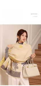 Detail of warm winter scarf with ginkgo leaf pattern draped over model's shoulder