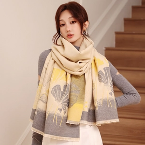 Detail of warm winter scarf with yellow ginkgo leaf print and soft tassel edges