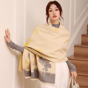Detail of soft ginkgo leaf pattern scarf with fine fringe on thick beige knit fabric