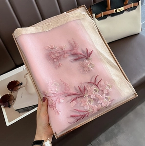 Detail of pink embroidered silk wool scarf with floral patterns in a luxury gift box