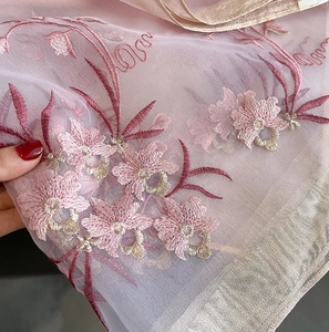 Detail of pink silk wool shawl with intricate floral embroidery and gold trim border