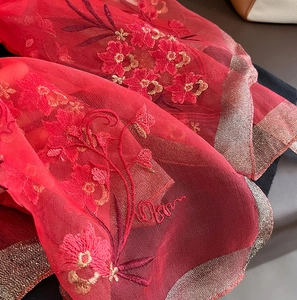Detail of red silk wool scarf featuring floral embroidery and metallic lurex woven edges