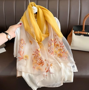 Detail of silk wool scarf showing yellow and beige stitching with floral embroidery