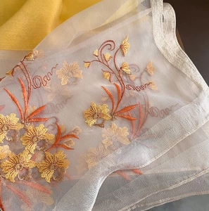 Detail showing intricate gold and orange floral embroidery on sheer silk wool fabric scarf