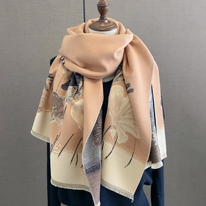 Detail of warm scarf with ginkgo leaf pattern and short fringes on wooden mannequin