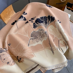 Detail of winter scarf with ginkgo leaf pattern and delicate tassels on a wooden chair