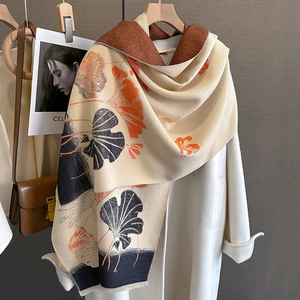 Detail view of gingko leaf print scarf draped on a coat for elegant winter styling