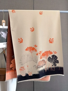 Detailed texture of beige scarf with orange ginkgo leaf prints and fine fringe edges