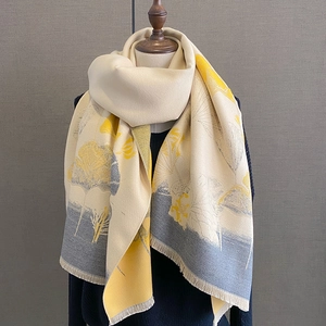 Detail of warm beige scarf with yellow leaf pattern and soft fringe on mannequin