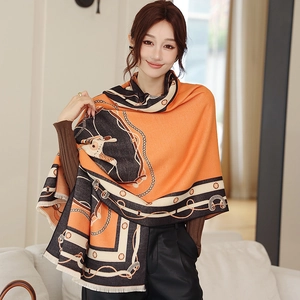 Détail d'écharpe en cachemire avec motifs équestres orange et finitions à franges