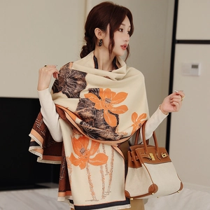 Detailed view of beige cashmere-like scarf featuring orange lotus prints and fine fringe