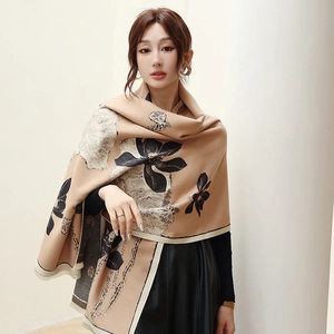 Close-up of thick mustard green scarf with black floral prints and soft tassel edges