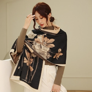 Close-up of elegant black scarf featuring beige lotus patterns and delicate tassels