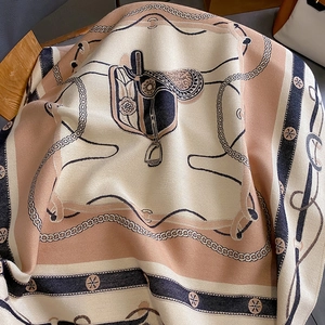 Détail macro d'une écharpe châle à motif équestre avec selles et chaînes métalliques