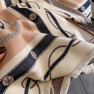 Détail macro d'une écharpe effet cachemire avec motifs de chaînes et bords frangés