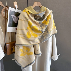 Detailed view of beige cashmere feel shawl with yellow floral pattern and fringe edge