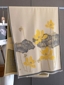 Detail of elegant beige lotus print shawl with fringe on a gray textured background