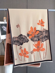 Detailed view of thick cashmere scarf featuring orange lotus patterns and fringe edges