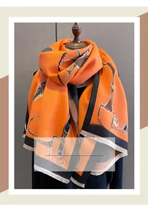 Detail of horse-bit equestrian print on thick cashmere-like orange scarf with tassels