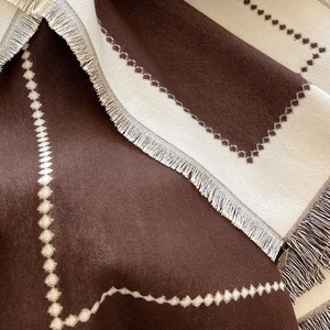 Detail of soft cashmere feel scarf with geometric patterns and neat tassel edges