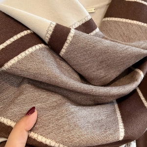 Close-up of soft color-block cashmere scarf with striped texture and fringe detail