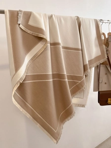 Detail of color-block scarf with geometric lines and soft fringed edges on a hanger